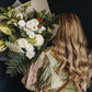 Bouquet of neutral tone flowers being held over the shoulder by a woman with long blonde hair. Clare florist that offers local delivery.