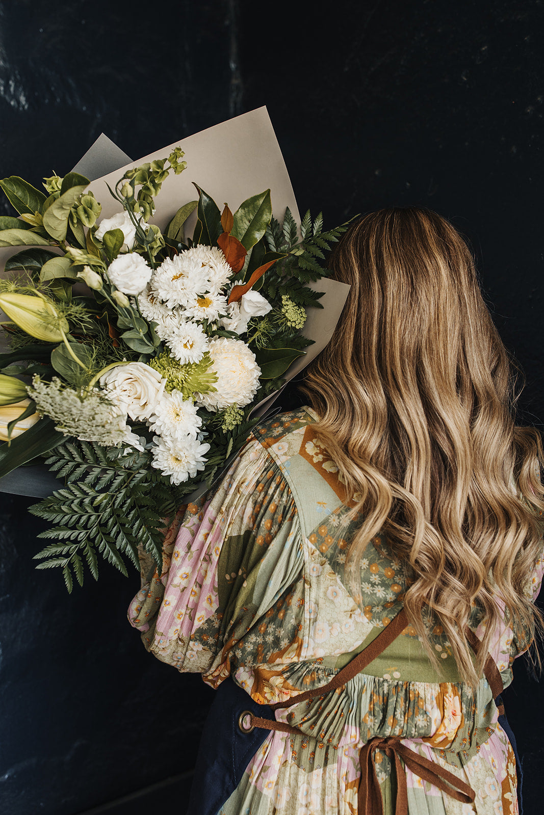 Bouquet of neutral tone flowers being held over the shoulder by a woman with long blonde hair. Clare florist that offers local delivery.