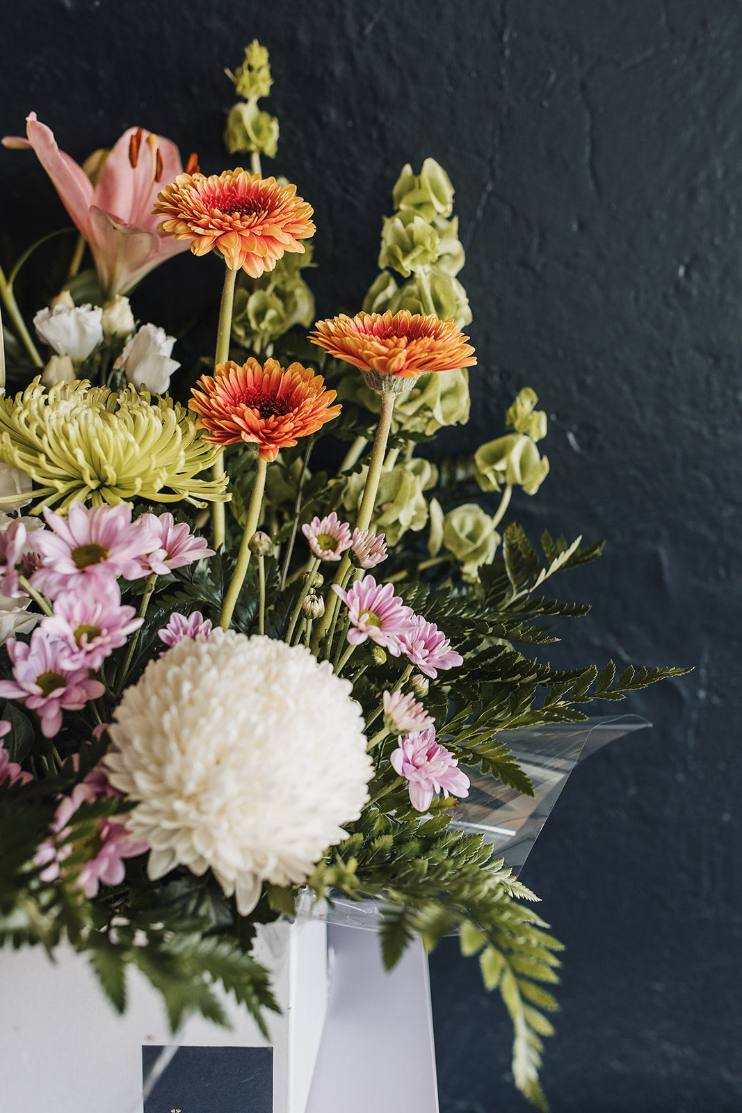 A closer view of the box arrangement with gerberas, chrysanthemums and fern foliage