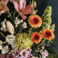 A view of the arrangement from above showing open lillies, gerberas, lisianthus, a spider chrysanthemum and daisy chrysanthemums