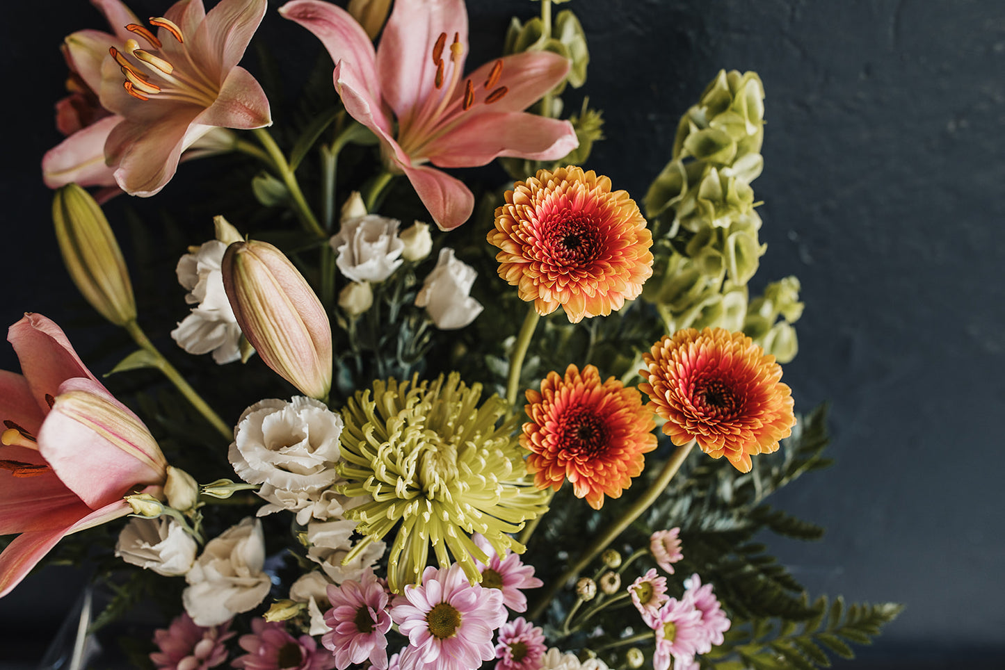 A view of the arrangement from above showing open lillies, gerberas, lisianthus, a spider chrysanthemum and daisy chrysanthemums
