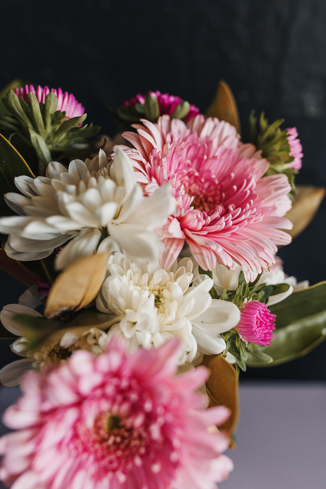 A close up on seasonal flowers, chrysanthemums, gerberas and asters with magnolia foliage