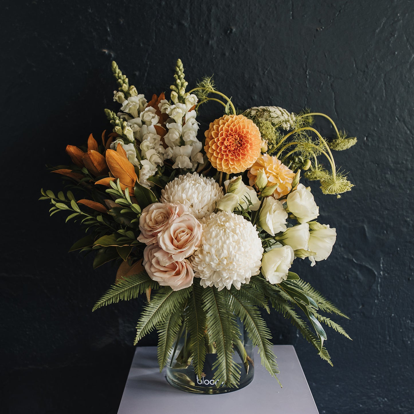 Luxury arrangement of premium flowers for  Delivery in Clare Valley. A large glass vase with snapdragons, lisianthus, roses, chrysanthemums and dahlias complimented with magnolia leaves, box and fern.